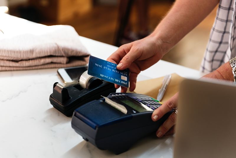 Man holding a debit card and working a credit card processing machine